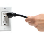 A woman unplugs an electrical cord